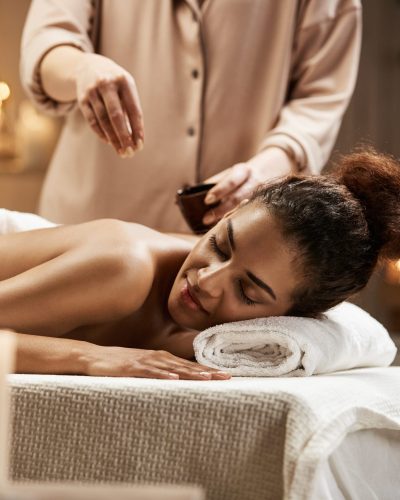 Tender beautiful african girl relaxing enjoying healthy spa massage with oil.